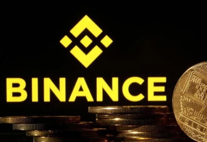 Đồng tiền Bitcoin và biểu tượng Binance. (Ảnh: Reuters/TTXVN)