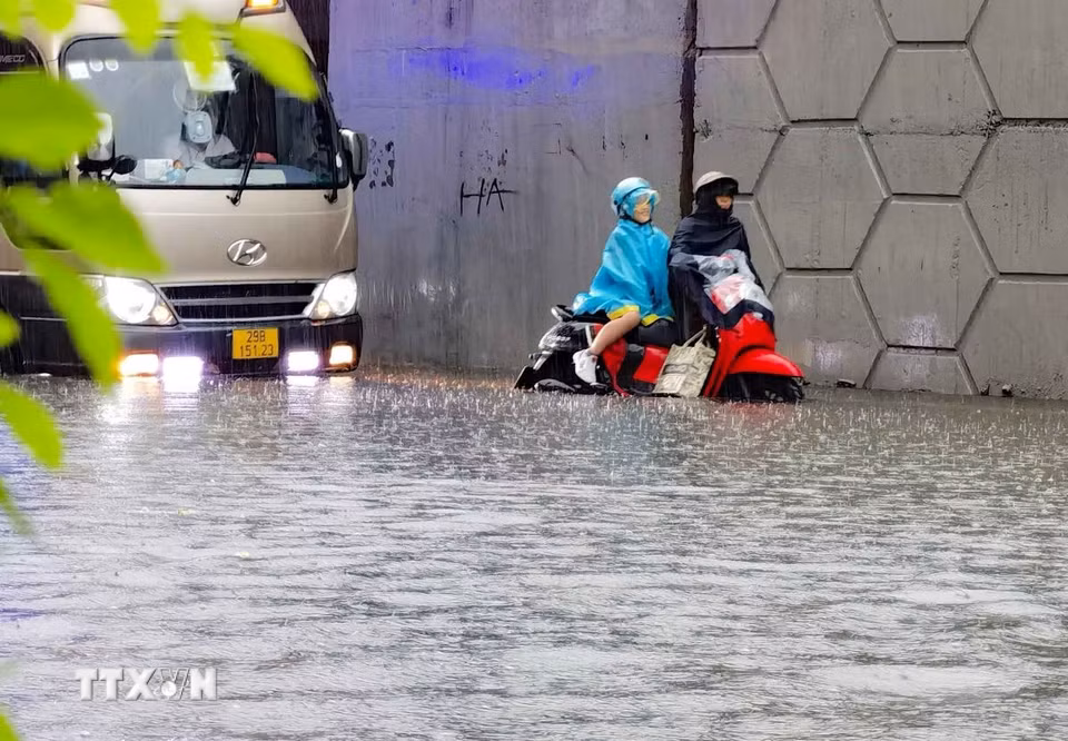 Người dân phải dắt xe khi đi qua điểm bị ngập trên đường Minh Khai, đoạn chân cầu Vĩnh Tuy (chiều 30/9/2025). (Ảnh: Thanh Tùng/TTXVN)