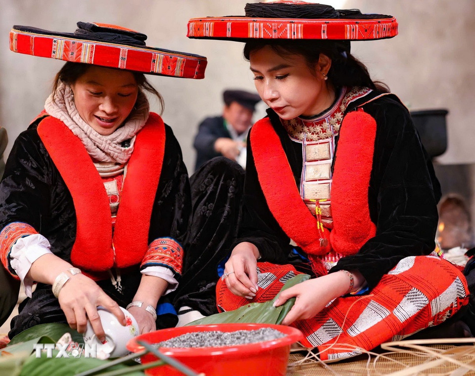 Nữ du khách tới từ Hà Nội trong trang phục truyền thống của người Dao đỏ huyện Nguyên Bình háo hức cùng gói bánh chưng gù ngày Tết. (Ảnh: Thanh Tùng/TTXVN)