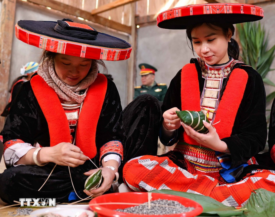 Nữ du khách tới từ Hà Nội trong trang phục truyền thống của người Dao đỏ huyện Nguyên Bình háo hức cùng gói bánh chưng gù ngày Tết. (Ảnh: Thanh Tùng/TTXVN)