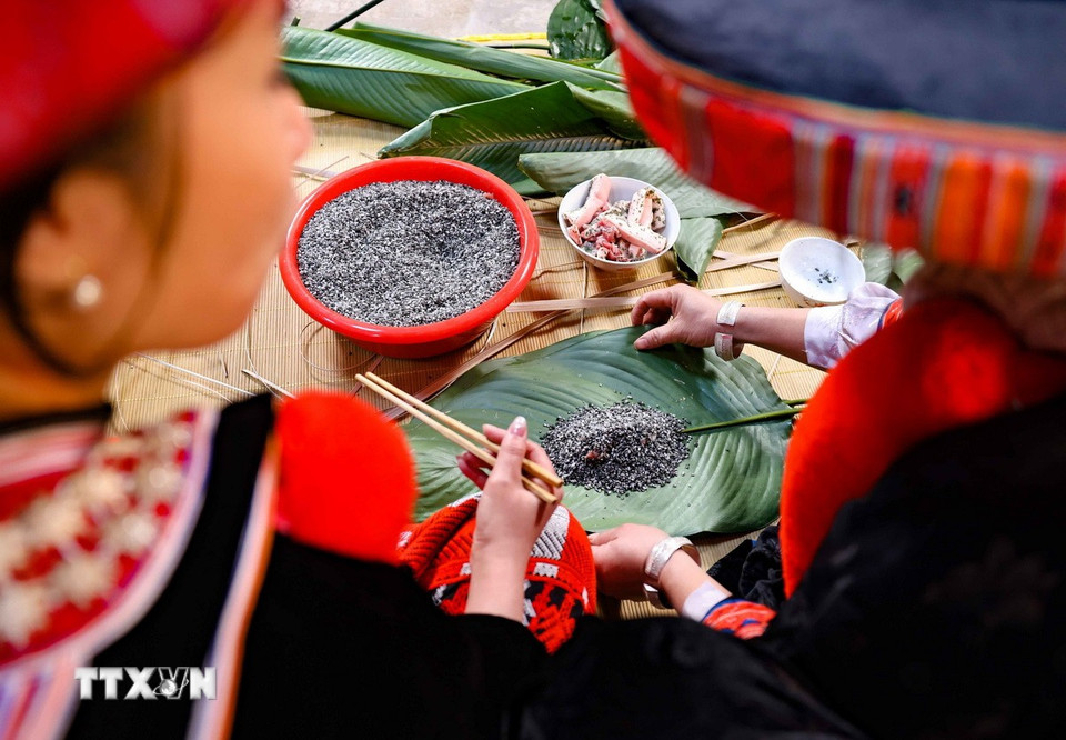 Trong các gia đình người Dao, gói bánh chưng là công việc của phụ nữ. Các bà, các chị vừa gói bánh vừa chỉ bảo cho những người con gái trong nhà học làm theo. (Ảnh: Thanh Tùng/TTXVN)