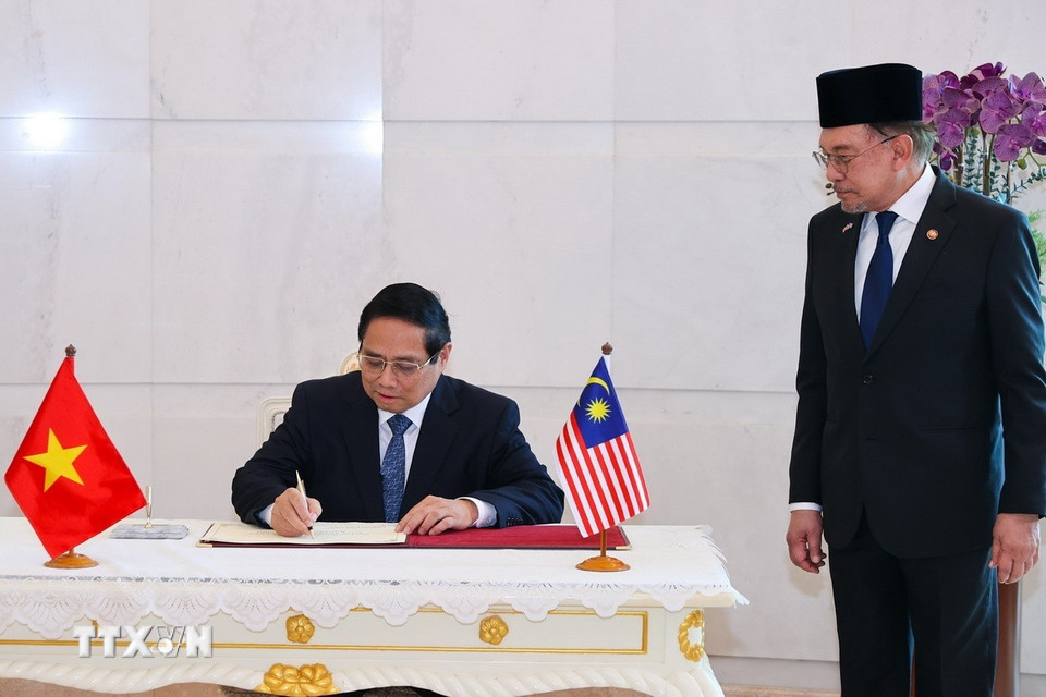 Thủ tướng Phạm Minh Chính ký sổ lưu niệm tại Phủ Thủ tướng Malaysia. (Ảnh: Dương Giang/TTXVN)