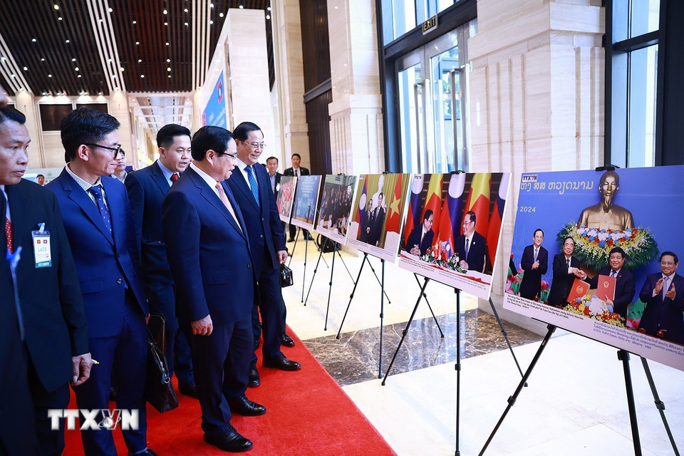 Thủ tướng Phạm Minh Chính và Thủ tướng Lào Sonexay Siphandone tham quan trưng bày ảnh về hợp tác giữa hai nước. (Ảnh: Dương Giang/TTXVN)