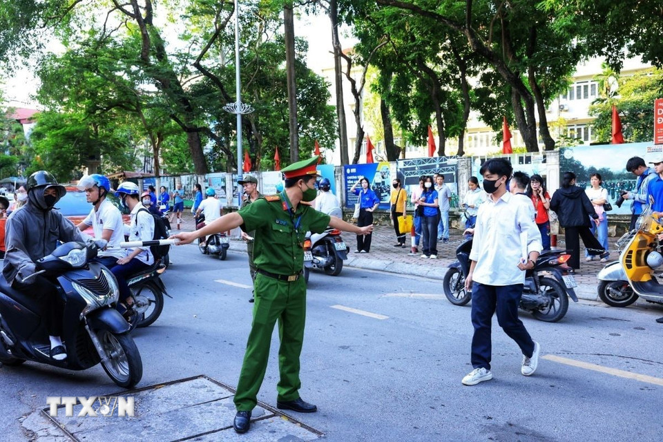 Lực lượng công an phường Khương Đình hướng dẫn người nhà và thí sinh tại điểm thi trường liên cấp Khương Hạ, quận Thanh Xuân. (Ảnh: Tuấn Anh/TTXVN)