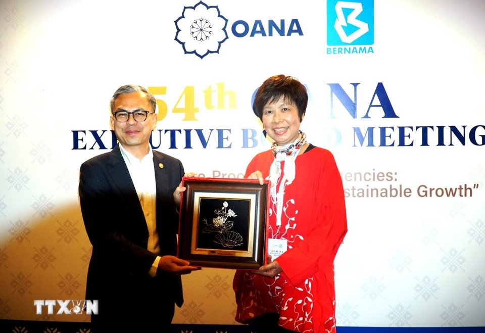 Tổng Giám đốc TTXVN Vũ Việt Trang tặng quà Bộ trưởng Bộ Truyền thông Malaysia Fahmi Fadzil. (Ảnh: Hằng Linh/TTXVN)