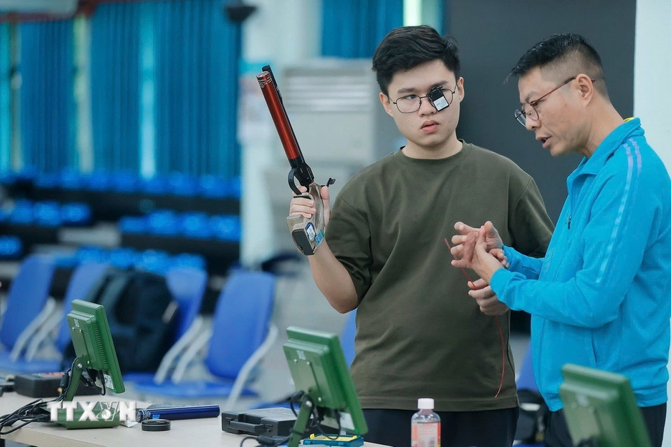 Huấn luyện viên Nguyễn Quốc Cường trao đổi với xạ thủ Lại Công Minh trong buổi tập. (Ảnh: Minh Quyết/TTXVN)