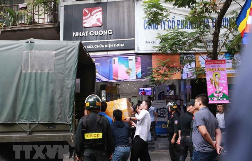 Cảnh sát kiểm tra, khám xét và đưa các kiện hàng lên xe tại cửa hàng điện thoại Nhật Cường mobile ở 33 Lý Quốc Sư, Hà Nội. (Ảnh: Doãn Tấn/TTXVN) 
