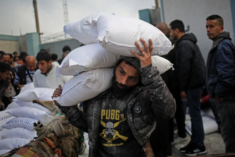 Người dân nhận hàng viện trợ nhận đạo tại trung tâm phân phối của UNRWA ở thành phố Rafah, Dải Gaza. (Ảnh: AFP/TTXVN)