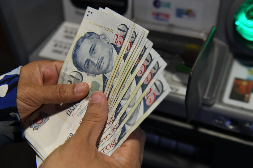 Người dân rút tiền đô la Singapore từ máy rút tiền tự động (ATM) tại Singapore. (Ảnh: AFP/TTXVN)