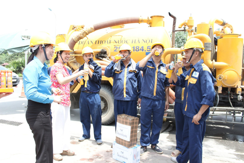 Lãnh đạo Công ty TNHH MTV Thoát nước Hà Nội phát nước uống, động viên người lao động làm việc trong những ngày nắng nóng. (Ảnh: Mạnh Khánh/TTXVN)