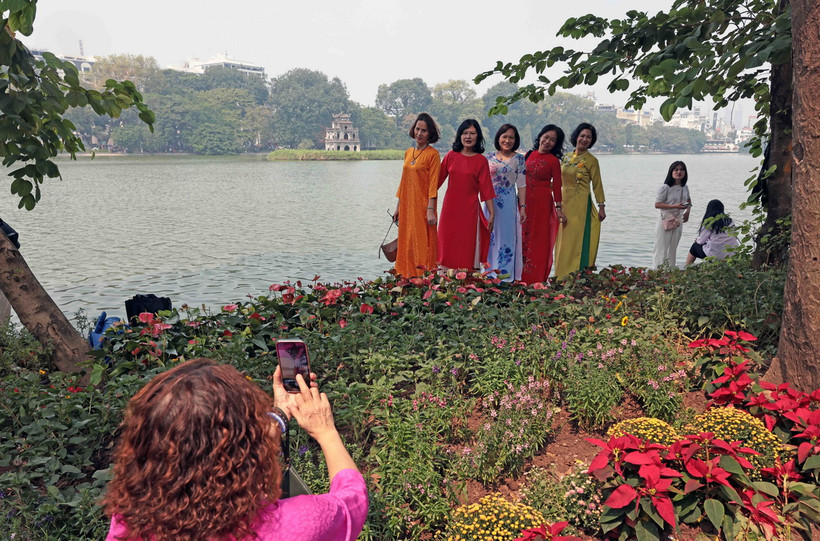 Người dân lưu lại hình ảnh áo dài bên Hồ Gươm trong những ngày nắng đẹp của mùa Thu. (Ảnh: Trần Việt/TTXVN)