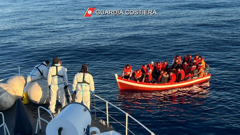 Tàu của lực lượng bảo vệ bờ biển Italy tiếp cận thuyền chở người di cư trong chiến dịch giải cứu ngoài khơi Italy. (Ảnh: AFP/TTXVN)