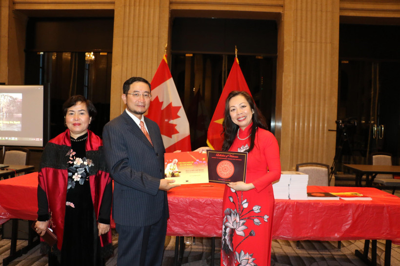 Giáo sư Julie Nguyễn (áo đỏ) tặng Đại sứ Việt Nam tại Canada Phạm Cao Phong và phu nhân hai tác phẩm "Bài ca Hồ Chí Minh" và "Lời ru nước Việt" mà giáo sư vừa ra mắt. (Ảnh: Vũ Quang Thịnh/TTXVN)