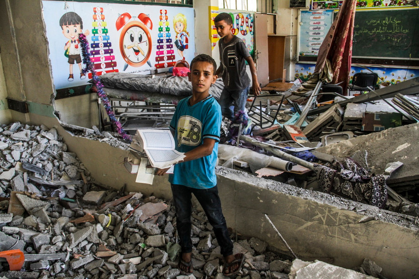 Trẻ em bên đống đổ nát của trường học bị trúng không kích của Israel tại thành phố Gaza ngày 25/6. (Ảnh: THX/TTXVN)