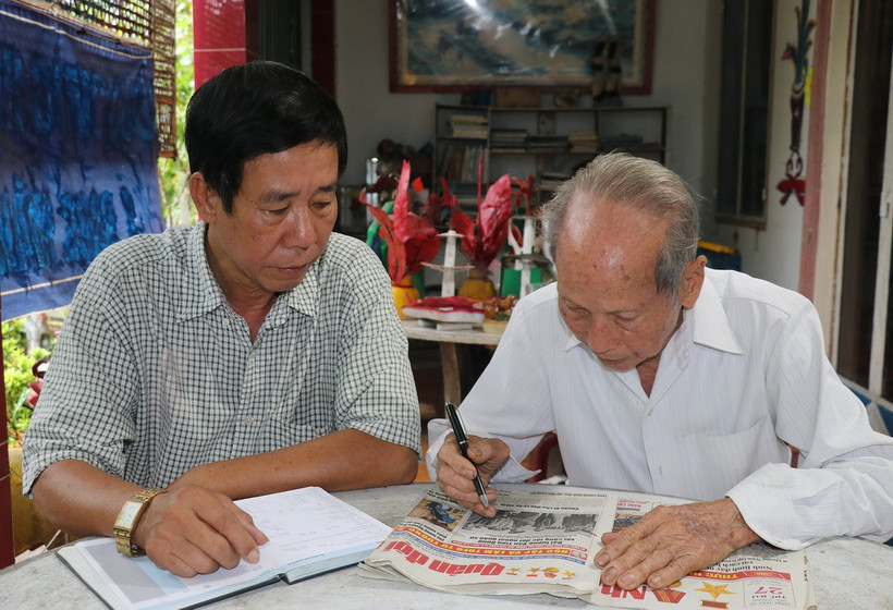 Ông Nguyễn Văn Thọ (phải) và con trai Nguyễn Thanh Hà đọc thông tin ở mục tìm thân nhân liệt sỹ trên báo. (Ảnh: Hữu Chí/TTXVN)
