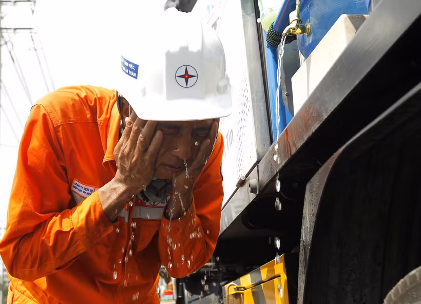 Công nhân điện lực giải nhiệt tạm thời trong quá trình thi công dưới trời nắng nóng trên 41 độ C tại Thành phố Hồ Chí Minh. (Ảnh: Thanh Vũ/TTXVN)
