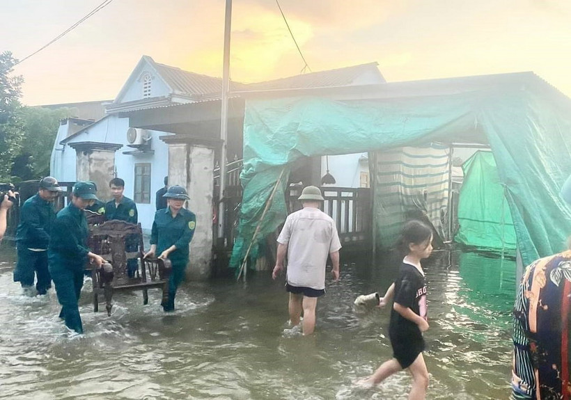 Lực lượng dân quân cơ động giúp người dân di chuyển đồ đạc ra khỏi khu vực nước ngập. (Ảnh: TTXVN phát)