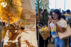 Người dân thích thú với những món quà lưu niệm độc đáo làm từ tre mây tại các gian hàng. (Ảnh: Thanh Phong/Vietnam+)