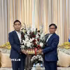 Đại sứ Phạm Việt Hùng (trái) tặng lãng hoa tới Đại sứ Lào Sisavath Inphachanh chúc mừng 50 năm Quốc khánh Lào. (Ảnh: Đỗ Sinh/TTXVN)