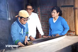 Nguyễn Thành Kiên đang giới thiệu cho du khách cách sao trà bằng chảo gang trên bếp lửa. (Ảnh: Hằng Trần/Vietnam+)