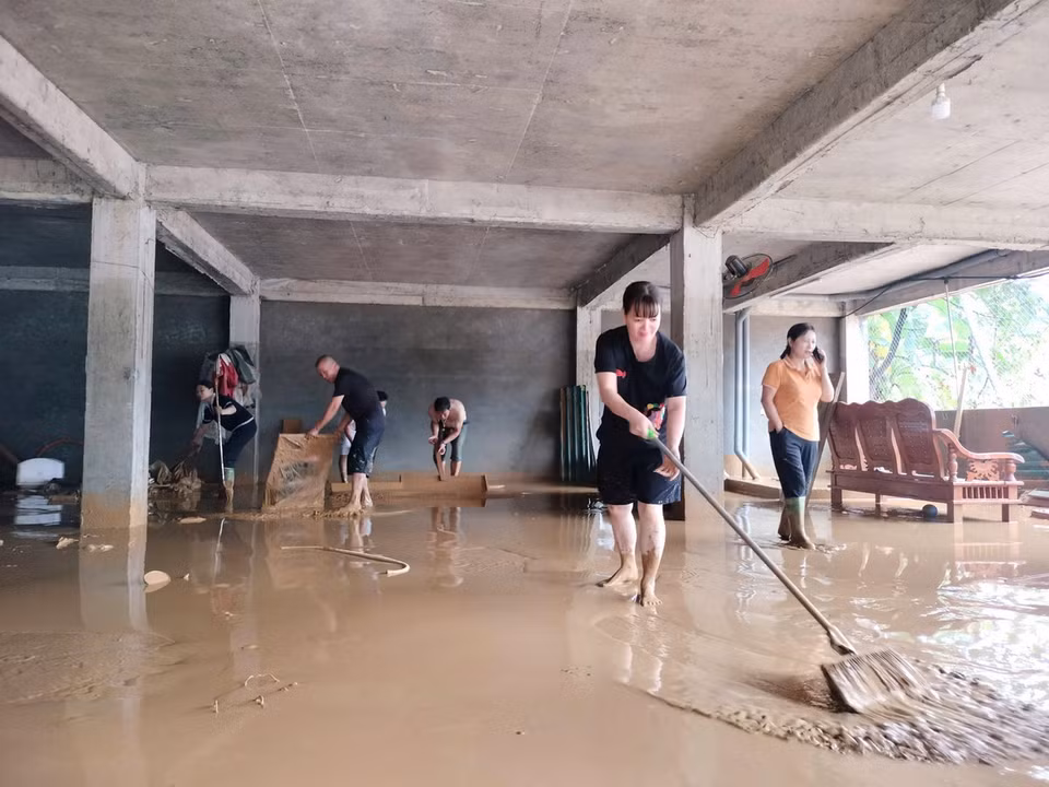 Người dân ở tổ 4, phường Minh Tân tranh thủ dọn dẹp khi nước rút. (Ảnh: Tuấn Anh/TTXVN)