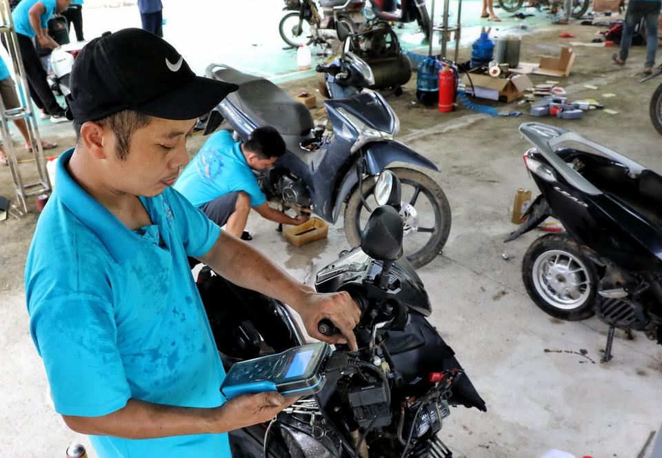 Thợ sửa xe máy Hội kỹ thuật xe máy Thanh Hóa dùng thiết bị kiểm tra lỗi trên xe máy. (Ảnh: Tuấn Anh/TTXVN)