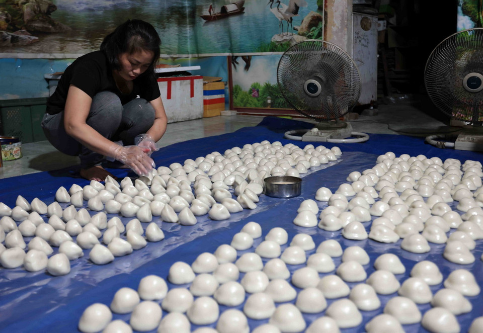 Bánh được xoa lớp mỡ để đóng gói. (Ảnh: Trần Việt/TTXVN)