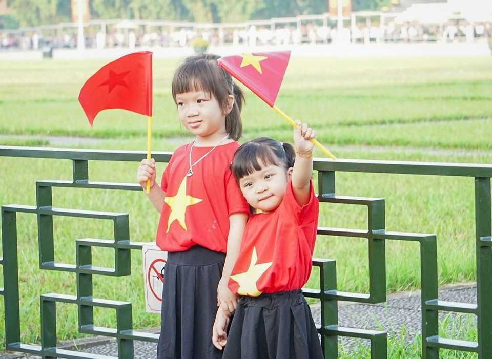 Các em nhỏ được bố mẹ đưa đi dự lễ thượng cờ trong ngày Quốc khánh 2/9. (Ảnh: Khánh Hòa/TTXVN)