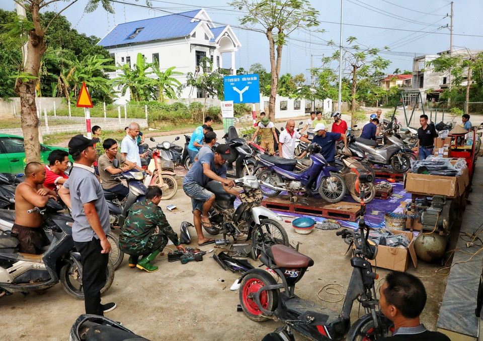 Những người thợ sửa xe máy của Hội kỹ thuật xe máy Thanh Hóa sửa xe cho người dân tại địa điểm Nhà văn hóa tổ 13, phường Yên Ninh trong sáng 18/9. (Ảnh: Tuấn Anh/TTXVN)