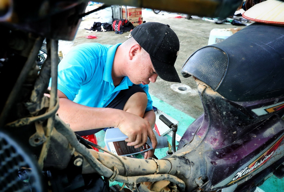 Những người thợ sửa xe máy của Hội kỹ thuật xe máy Thanh Hóa tranh thủ từng phút, cố gắng sửa được nhiều xe nhất có thể cho người dân. (Ảnh: Tuấn Anh/TTXVN)