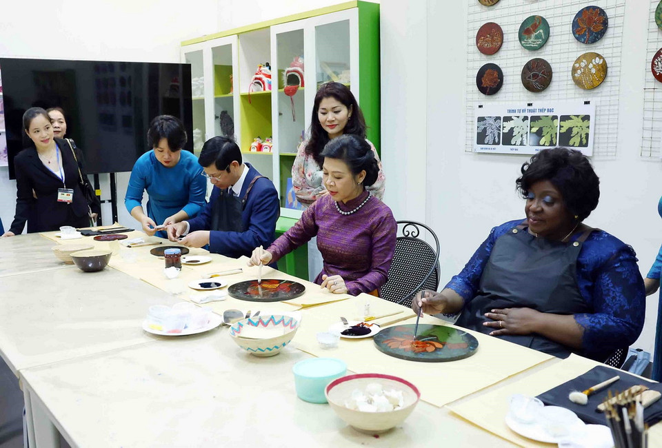 Phu nhân Tổng Bí thư, Chủ tịch nước Tô Lâm, bà Ngô Phương Ly và Phu nhân Tổng thống Mozambique Filipe Jacinto Nyusi, bà Isaura Ferrao Nyusi trải nghiệm sáng tác tranh sơn mài tại Bảo tàng Mỹ thuật Việt Nam. (Ảnh: Phạm Kiên/TTXVN)
