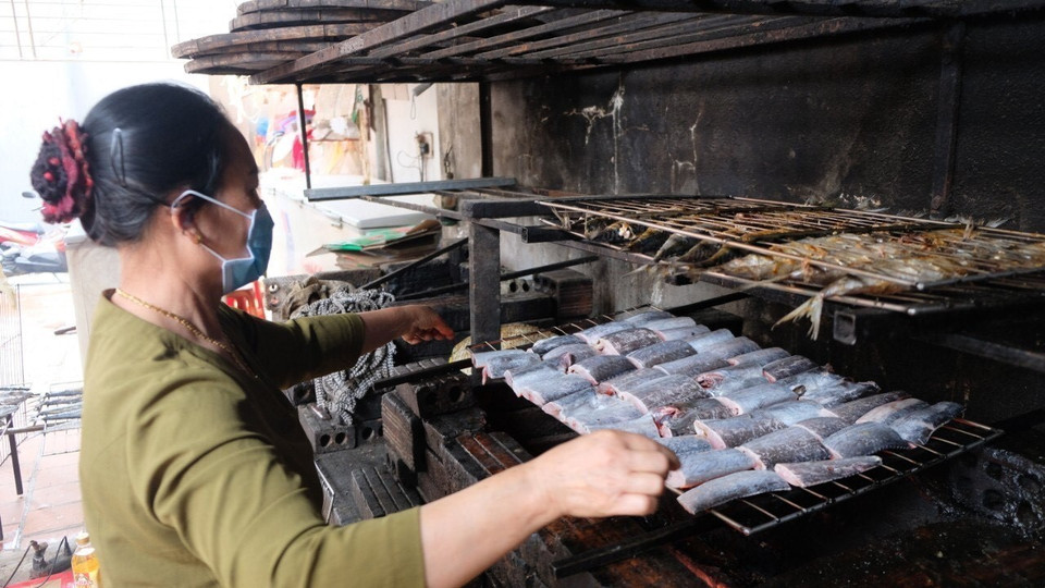 Đưa cá lên giàn nướng than. (Ảnh: TTXVN phát)