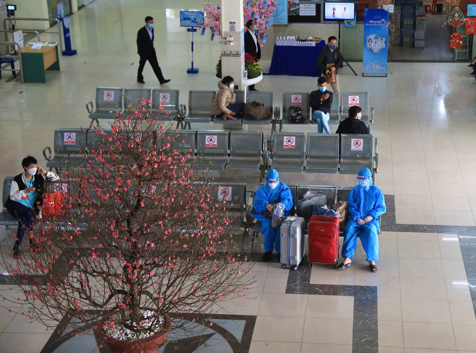 Hai hành khách đã mặc đồ bảo hộ trước khi chuẩn bị di chuyển tuyến Hà Nội-Hà Giang. (Ảnh: Hoàng Hiếu/TTXVN)