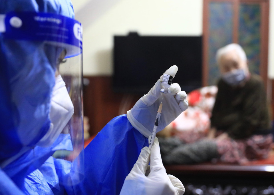 Y tá Hoàng Thuỳ Linh (trạm y tế phường Hàng Bài, Hoàn Kiếm) chuẩn bị tiêm vaccine Pfizer cho người cao tuổi, có bệnh lý nền ngay tại nhà. (Ảnh: Hoàng Hiếu/TTXVN)