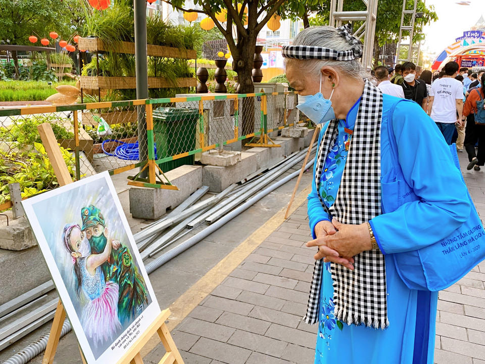 Một vị khách tham quan gian triển lãm tranh về chủ đề Thành phố Hồ Chí Minh và cuộc chiến chống dịch COVID-19. (Ảnh: Hồng Giang/TTXVN)