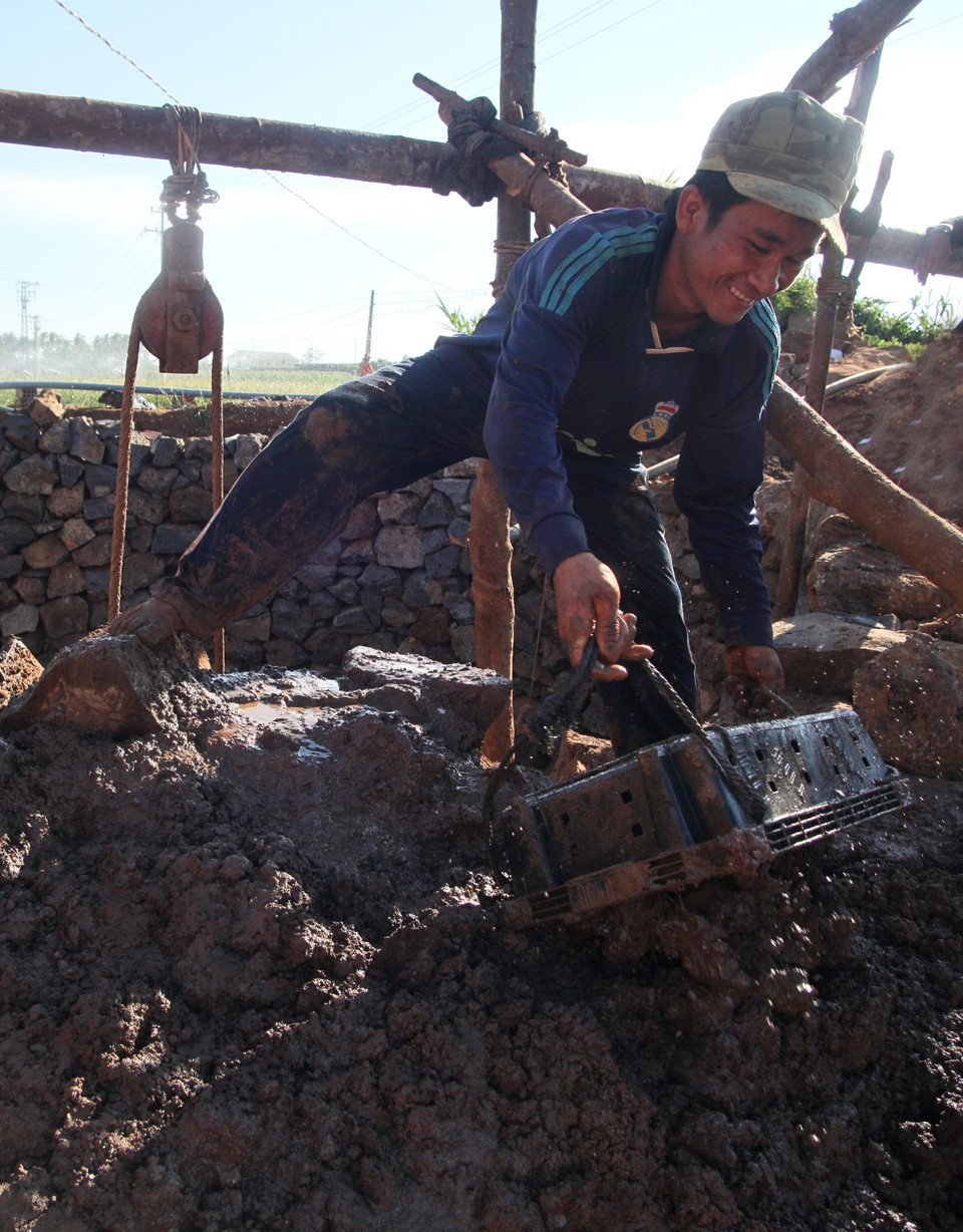 Những khối bùn đất từ dưới giếng sẽ được đổ ra xung quanh, làm chắc thành giếng luôn. (Ảnh: Doãn Đức/Vietnam+)