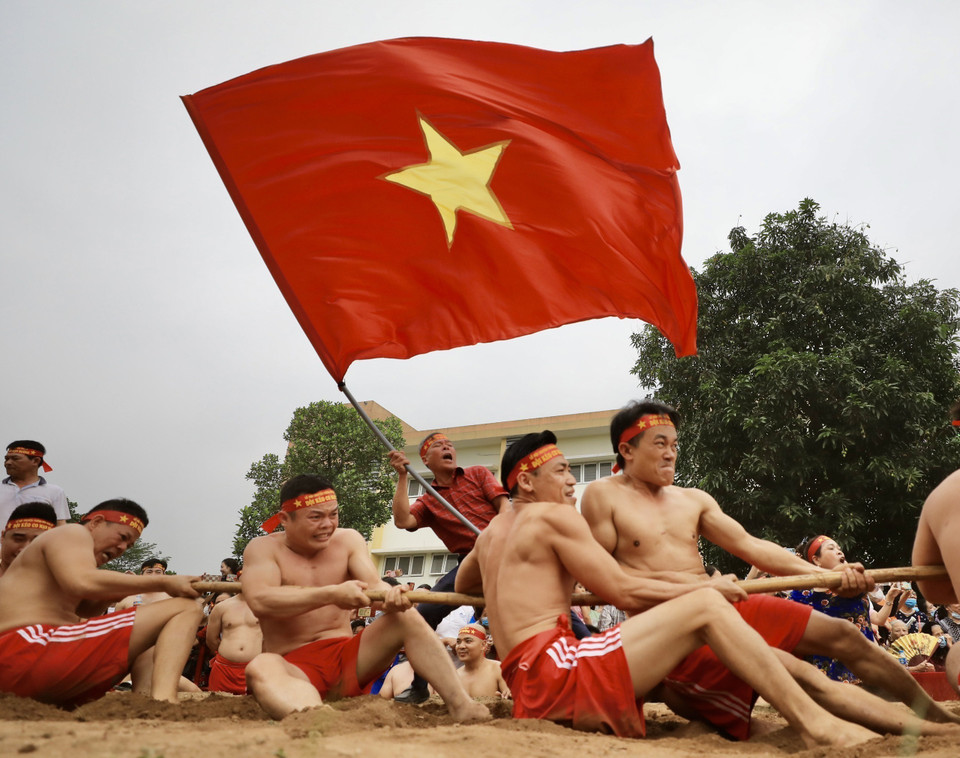 “Kéo co ngồi” không chỉ thể hiện sức khỏe của mỗi người chơi mà còn là tinh thần đoàn kết giữa người kéo co, người chạy cờ, người cổ động. (Ảnh: Nhật Anh/TTXVN)