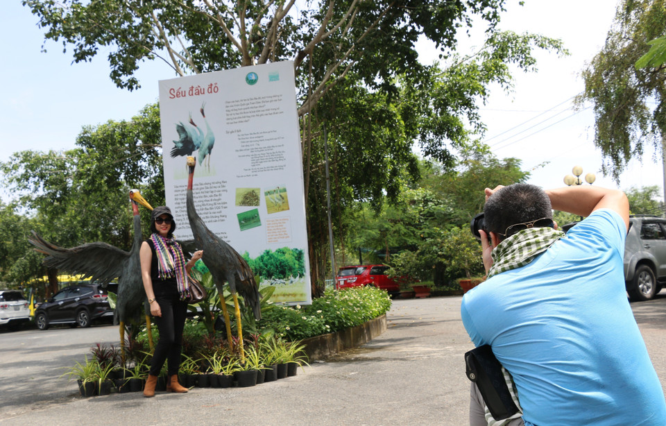 Khách du lịch chụp ảnh lưu niệm với biểu tượng Sếu đầu đỏ. (Ảnh: Chương Đài/TTXVN)