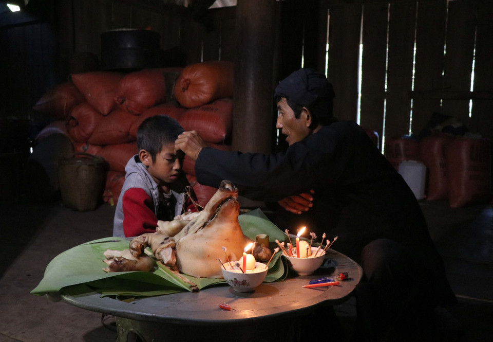 Thầy cúng lấy tiết gà đánh dấu lên trán cho trẻ nhỏ để cầu xin thần linh, tổ tiên phù hộ cháu nhỏ sức khỏe, học giỏi, mau trưởng thành và thành người tốt, góp sức xây dựng bản làng ấm no. (Ảnh: Nguyễn Xuân Tiến/TTXVN)