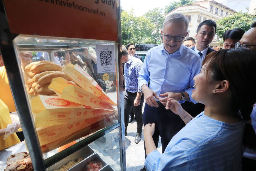 Thủ tướng Australia Anthony Albanese nghe giới thiệu về bánh mỳ patê truyền thống của Việt Nam. (Ảnh: Lâm Khánh/TTXVN)
