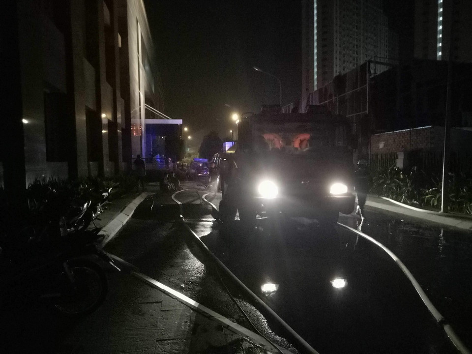 Cảnh sát Phòng cháy chữa cháy phun nước dập tắt đám cháy phát ra từ tầng hầm chung cư. (Ảnh: Thành Chung/TTXVN)