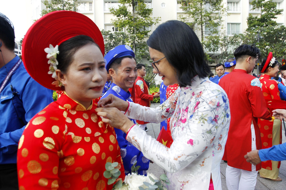 Lãnh đạo Thành đoàn Thành phố Hồ Chí Minh gắn huy hiệu Thành phố Hồ Chí Minh cho 100 cặp đôi tham dự Lễ cưới tập thể năm 2022. (Ảnh: Thanh Vũ/TTXVN)