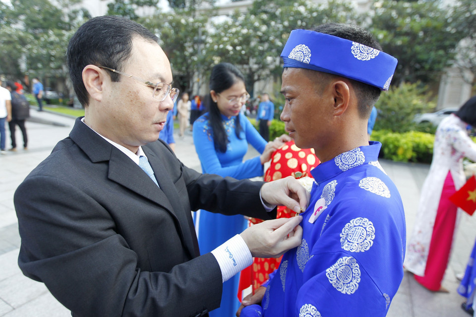 Ông Nguyễn Văn Hiếu, Phó Bí thư Thành ủy Thành phố Hồ Chí Minh gắn huy hiệu Thành phố Hồ Chí Minh cho 100 cặp đôi tham dự Lễ cưới tập thể năm 2022. (Ảnh: Thanh Vũ/TTXVN)