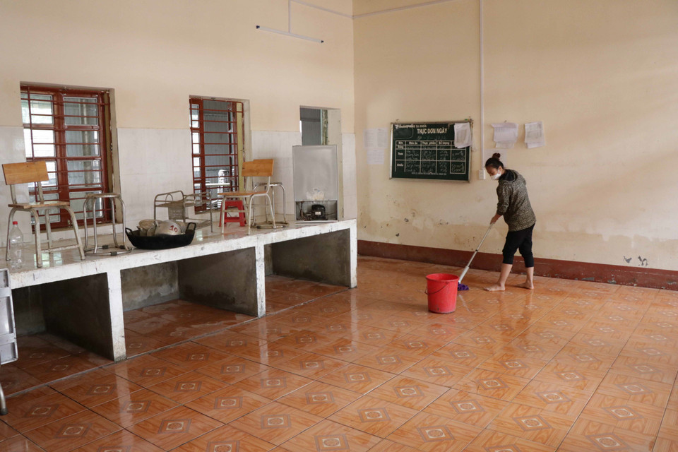 Giáo viên trường Trung học cơ sở Tạ Khoa dọn dẹp bếp ăn bán trú bị ngập bởi mưa lũ. (Ảnh: Hữu Quyết/TTXVN)