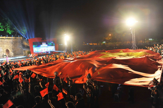 Lễ truyền lá cờ rộng 500m2, nặng 37kg tại điểm cầu Hoàng thành Thăng Long. (Ảnh: Minh Đức/TTXVN)