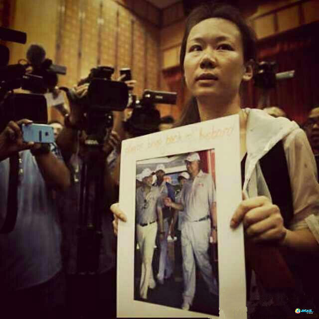 Ngày 30/1, một người phụ nữ cầm ảnh của người thân trên chuyến bay MH370, từ chối thông báo tất cả hành khách trên chuyến bay đã thiệt mạng. (Nguồn: QQ)