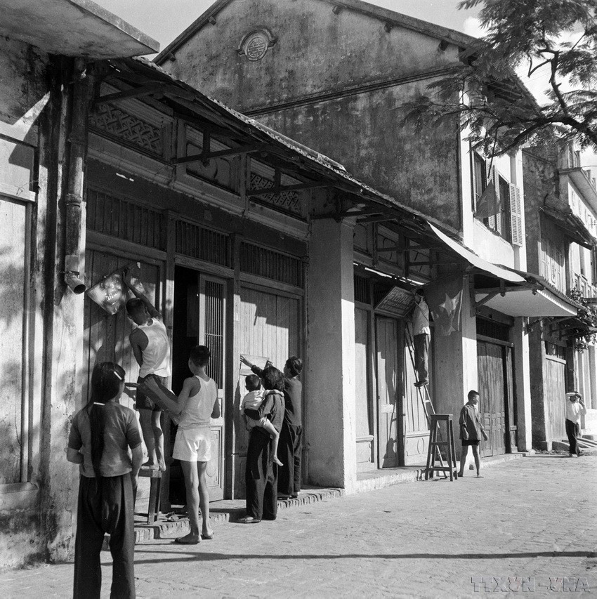 Từ sáng sớm, người dân Hà Nội treo cờ, khẩu hiệu trước cửa nhà, đón chào bộ đội về giải phóng Thủ đô. (Ảnh: Tư liệu TTXVN)