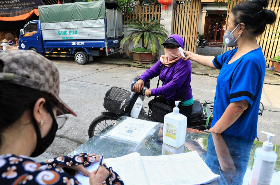 Tại thôn Thù Lỗ, xã Liên Hà, huyện Đông Anh, các bà, các mẹ thuộc hội Phụ nữ túc trực chốt phòng dịch ghi lại lịch trình đi lại của những người lạ đi vào thôn. (Ảnh: Tuấn Anh/TTXVN)
