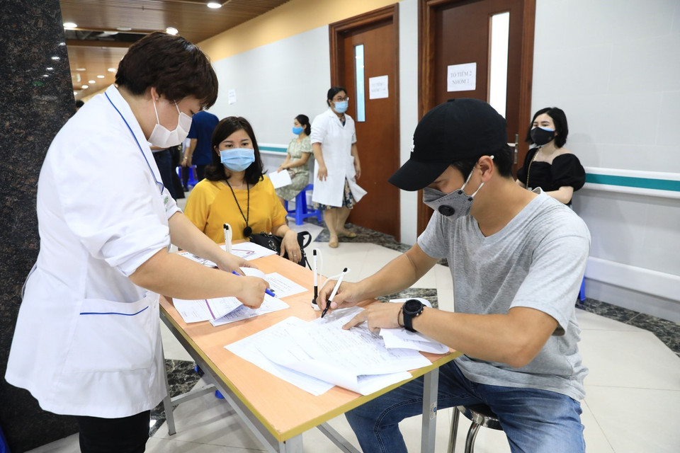 Các phóng viên khai thông tin cá nhân trước khi tiêm vaccine AstraZeneca. (Ảnh: Thành Đạt/TTXVN)