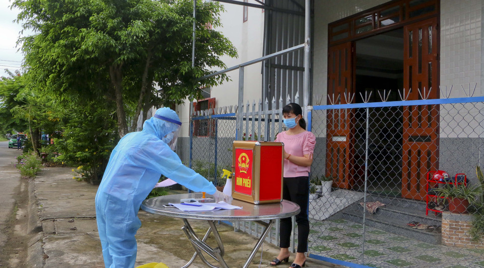 Cử tri đang thực hiện cách ly tại nhà tham gia bầu cử với thùng phiếu phụ được đưa tới tận nhà. (Ảnh: Duy Khương/TTXVN)